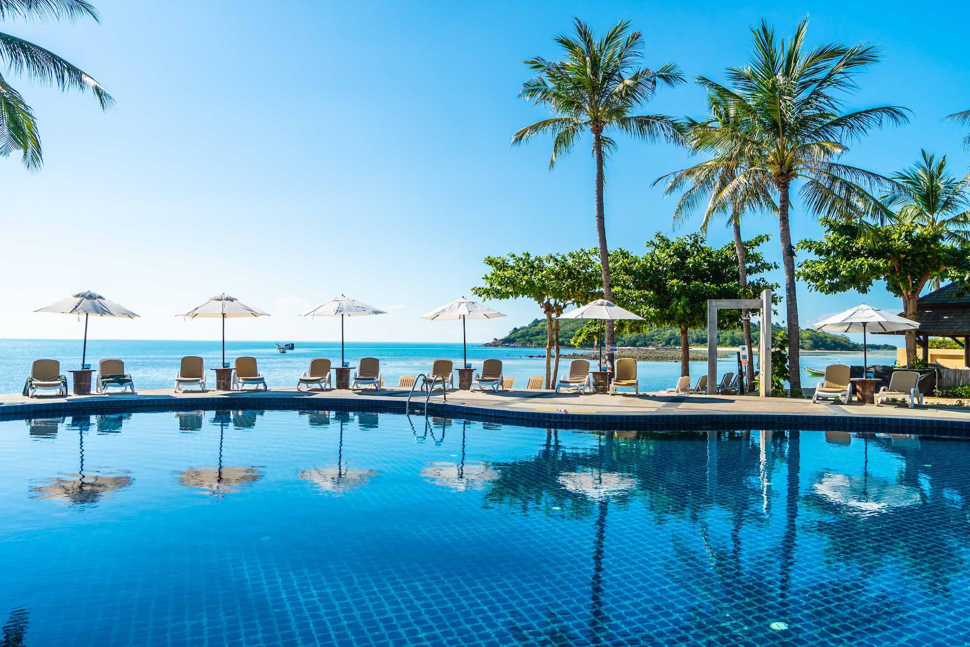 beautiful-tropical-beach-sea-with-umbrella-chair-around-swimming-pool